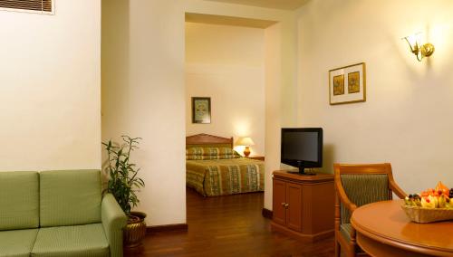 a living room with a bed and a table with a television at Hotel Abad Plaza in Cochin