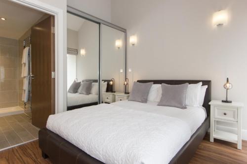 a bedroom with a large white bed and a mirror at Citystay - The Dales in Cambridge