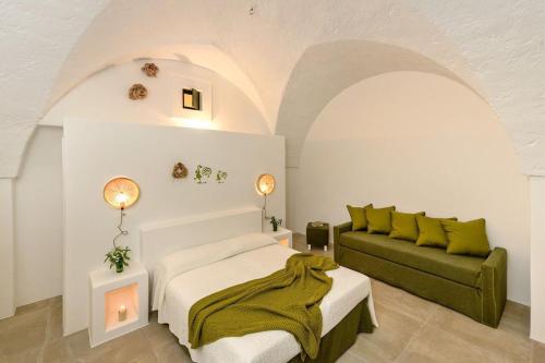 - une chambre avec un lit et un canapé vert dans l'établissement Masseria Narducci, à Montalbano