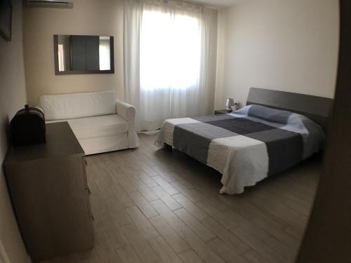 a bedroom with a bed and a couch and a window at Casa Vacanze Vespucci in Torre del Lago Puccini