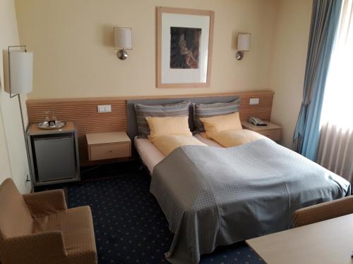 a hotel room with a bed and a chair at City Hotel in Schopfheim