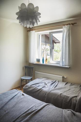 a bedroom with a bed and a chair and a window at Krauklis beach apartments in Saulkrasti