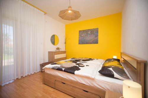 ein Schlafzimmer mit einem Bett und einer gelben Wand in der Unterkunft Vigo in Labin