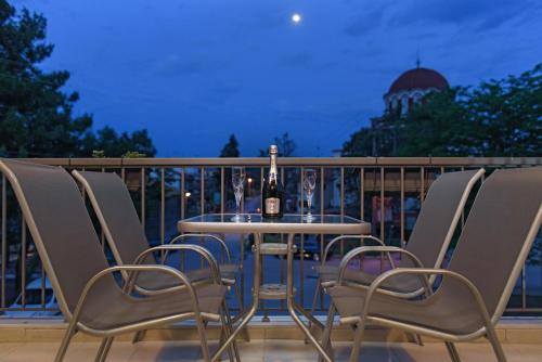 a table and chairs on a balcony with a bottle of wine at Armonia Lux Studios in Ierissos