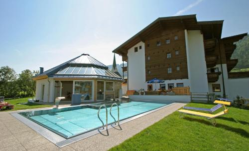 a house with a swimming pool next to a building at Hotel Simmerlwirt in Niederau