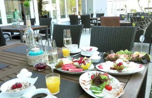 a wooden table with plates of food and glasses of orange juice at Caravelle Hotel im Park in Bad Kreuznach
