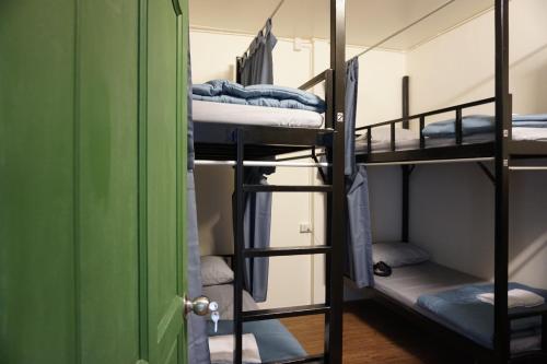 a room with three bunk beds and a green door at Krit Hostel in Bangkok