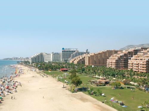 
a beach with a lot of palm trees and buildings at Apartamentos Marina d'Or Beach 2ª Linea in Oropesa del Mar
