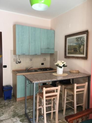 uma cozinha com armários azuis e uma mesa com bancos em Scilla Beach em Scilla
