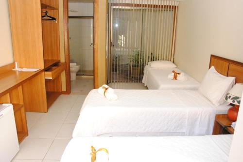 a hotel room with two beds and a bathroom at Pousada Cambucá de Cabo Frio in Cabo Frio