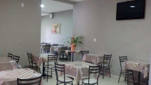 a dining room with white tables and chairs and a flat screen tv at Hotel Descanso in Descanso