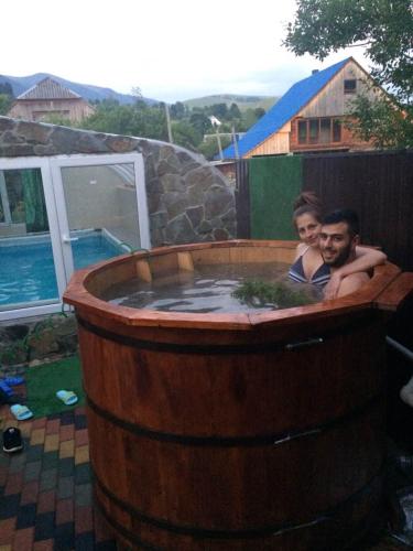 two men are sitting in a large wooden hot tub at Synevyrskyj Chardash in Synevyr