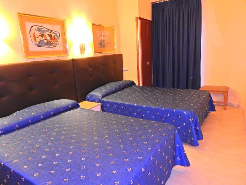 Habitación de hotel con 2 camas con sábanas azules en Hostal Bonavista en Calella