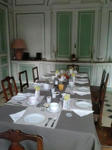 une grande table avec des assiettes et des serviettes dans l'établissement Le Chateau De La Vierge, à Bures-sur-Yvette