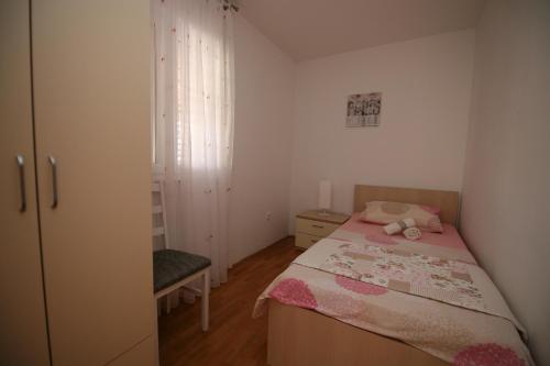 a small bedroom with a bed and a dresser at Apartman Mirica Solin in Solin