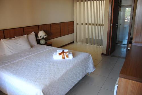 a bedroom with a white bed with a bow on it at Pousada Cambucá de Cabo Frio in Cabo Frio