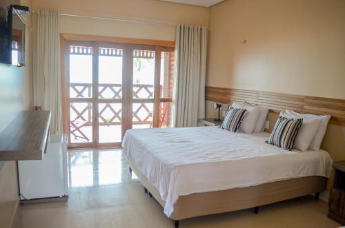 um quarto com uma cama grande e uma porta de vidro deslizante em Pousada Jagatá em Tutóia
