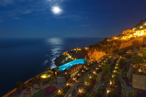a view of the ocean at night with a pool at Monastero Santa Rosa Hotel & Spa in Conca dei Marini