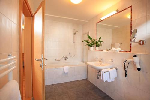 y baño con lavabo, bañera y espejo. en Appartements Barbara, en Westendorf
