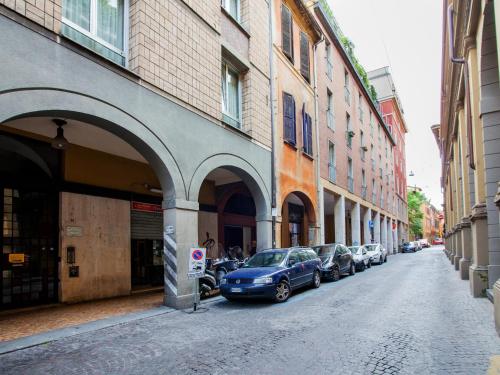 una calle de la ciudad con coches estacionados al lado de los edificios en Appartamenti Astoria en Bolonia