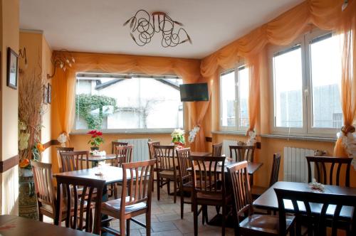 een eetkamer met tafels, stoelen en ramen bij Hotel Agata in Biella