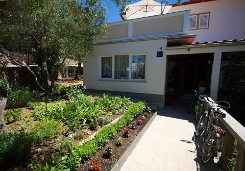a bike parked in front of a house with flowers at Balen Guest house in Rab