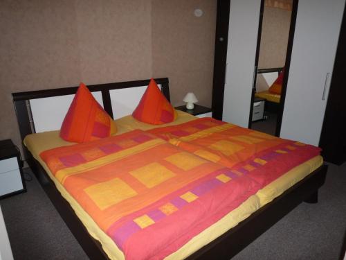 a bed with orange pillows and a colorful blanket at Zum alten Seemann in Pruchten