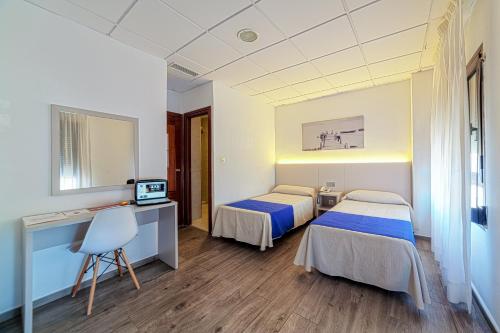 a hotel room with two beds and a desk at La Perla in Almería