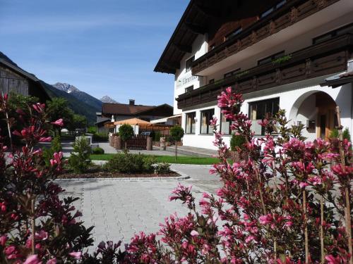 a courtyard with pink flowers in front of a building at Pension Elmerhof in Elmen