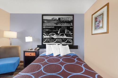 a hotel room with a bed with a train picture on the wall at Super 8 by Wyndham Havre De Grace Aberdeen Area in Havre de Grace