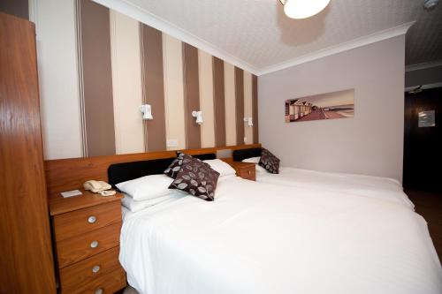 a bedroom with a large bed and a wooden dresser at Suncliff Hotel - OCEANA COLLECTION in Bournemouth