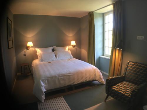 Un dormitorio con una cama y una silla y una ventana. en les jardins de la Matz, en Plouër-sur-Rance