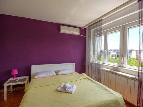 1 dormitorio con 1 cama con paredes de color púrpura y ventana en Apartments Sat, en Belgrado