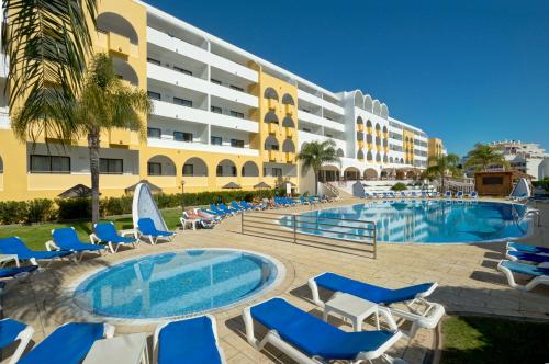 um resort com uma piscina e cadeiras e um edifício em Aparthotel Paladim & Alagoamar em Albufeira