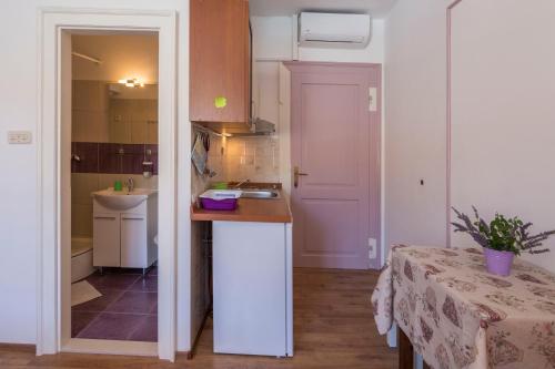 a kitchen with a counter and a sink and a table at Apartment Riva 5 in Komiža
