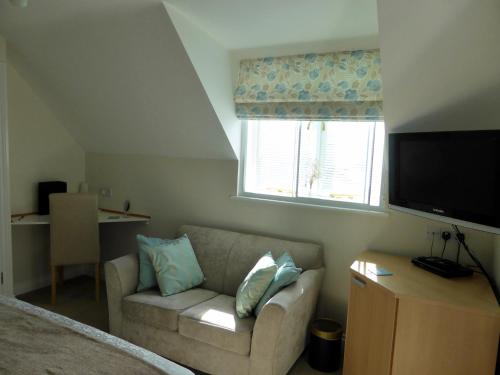 a living room with a couch and a television at Liongate House in Ilchester