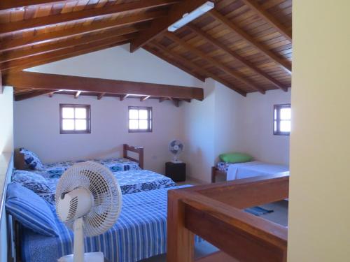 a bedroom with a blue bed and a wooden ceiling at Chalé no Caborê in Paraty