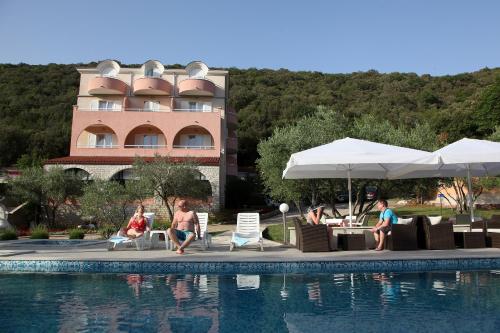 un grupo de personas sentadas alrededor de una piscina en un hotel en Hotel Carmen, en Krnica