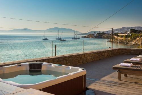 a bath tub sitting on a deck next to the water at Mykonos Beach Hotel in Mikonos