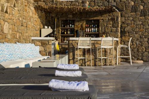 a room with chairs and a table and a counter with wine bottles at Mykonos Beach Hotel in Mikonos