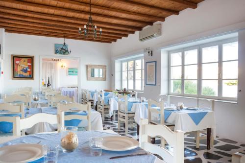 a restaurant with white tables and chairs and windows at Mykonos Beach Hotel in Mýkonos City