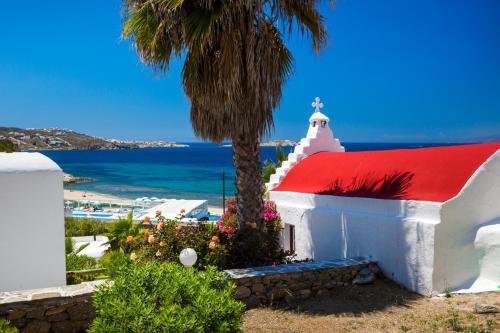 a church with a palm tree in front of the ocean at Mykonos Beach Hotel in Mýkonos City