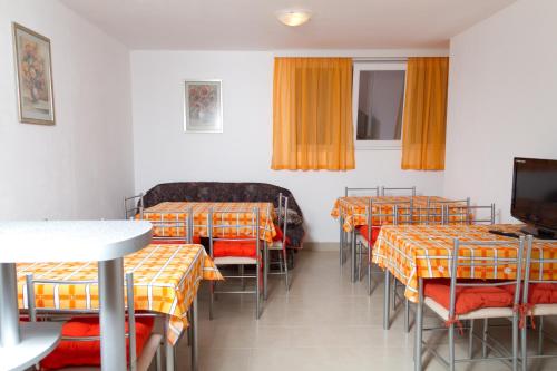 a room with several tables and chairs and a tv at Guest House Dobi in Primorsko