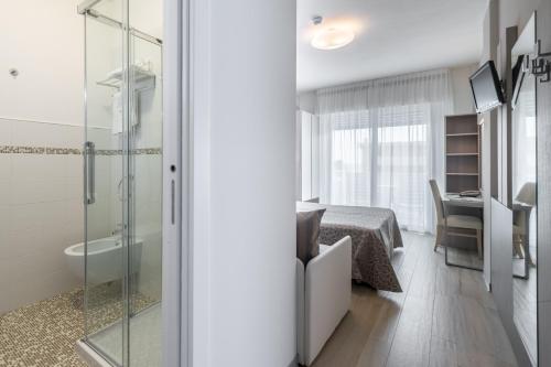 ein Badezimmer mit Bett und Glasdusche in der Unterkunft Hotel Mayer in Bibione