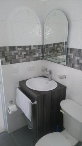 a bathroom with a sink and a toilet and a mirror at Villa Victoria in Sosúa