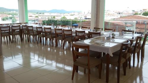 a dining room with tables and chairs and a large window at Pousada Max in Currais Novos