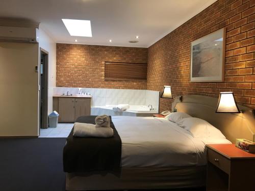 a bedroom with a large bed and a brick wall at Eltham Motor Inn in Eltham