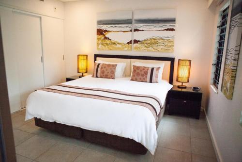 a bedroom with a large white bed with two lamps at 131 Temple Luxury Swimout Apt in Port Douglas