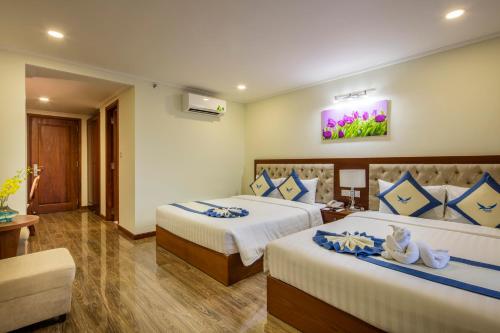 a bedroom with two beds with blue and white pillows at Apus Hotel in Nha Trang