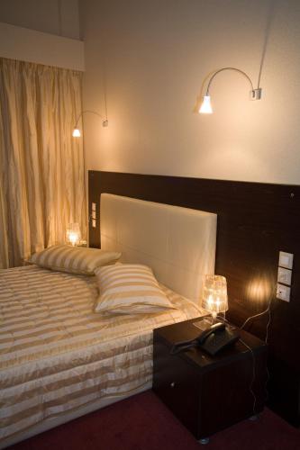 a bedroom with a bed with a telephone and lights at Olympic Star in Patra